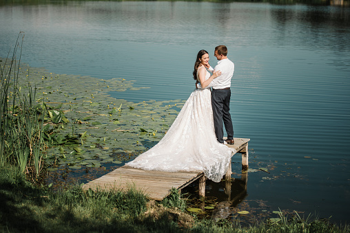 the bride and groom under the veil on the sunset by the river. the concept of romance and a beautiful wedding ceremony.