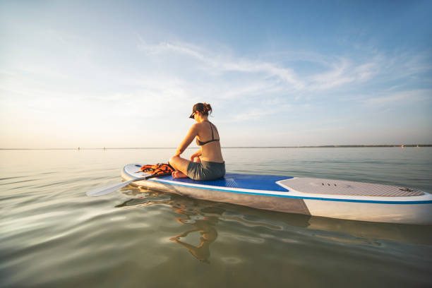 istock Young woman sup boarding alone at sunset 1404448814