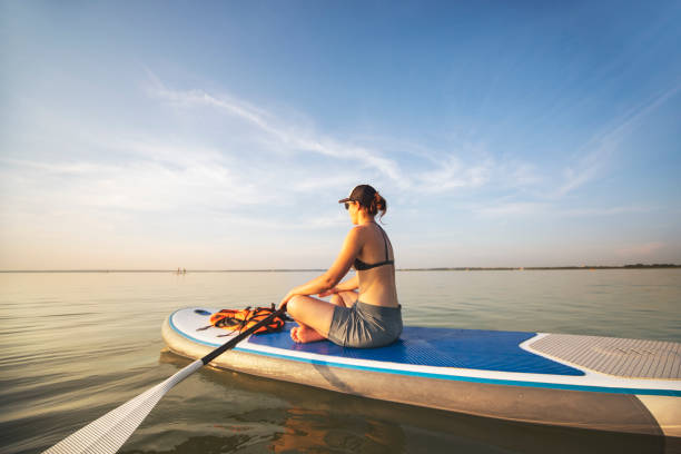istock Young woman sup boarding alone at sunset 1404448857