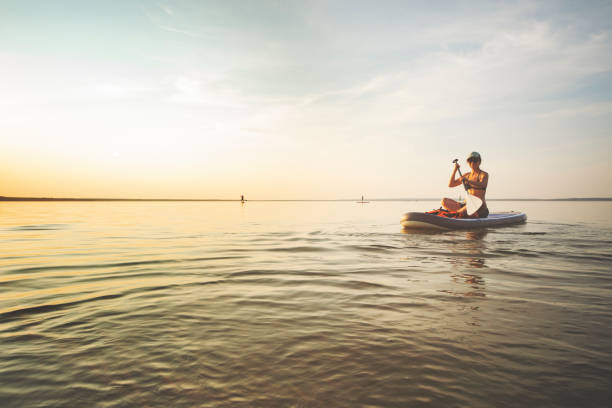 istock Young woman sup boarding alone at sunset 1404448903