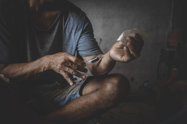 human hand of a drug addict and a syringe with narcotic syringe lying on the floor. 26 june, international day against drug abuse. - narcotic teenager cocaine drug abuse imagens e fotografias de stock