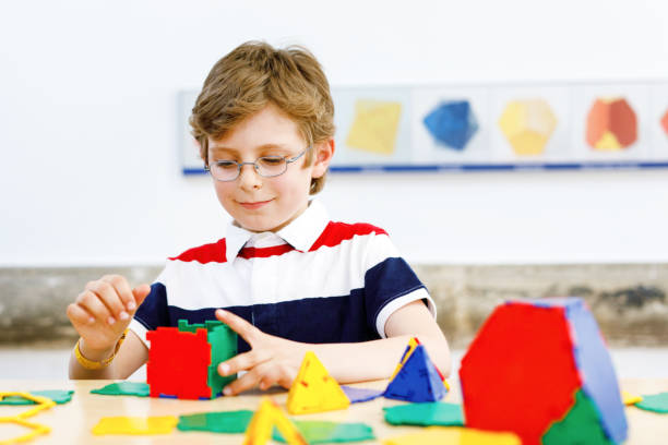 istock Happy kid boy with glasses having fun with building and creating geometric figures, learning mathematics and geometry 1404451325