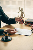 istock Business people or lawyers discussing contracts or business deals at a law firm. Justice advice service concept with hammer and goddess of justice beside, vertical image. 1404451497