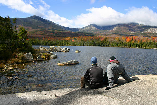 Couple at Katahdin - Maine A young couple pause in their hike to enjoy the colorful fall foliage on Mount Kathadin in remote Baxter State Park, Maine. mt katahdin stock pictures, royalty-free photos & images