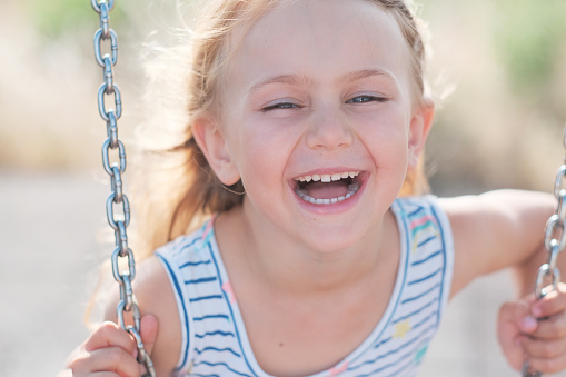 Portrait of redhead girl with freckles on summer blurred background. Cheerful and happy childhood