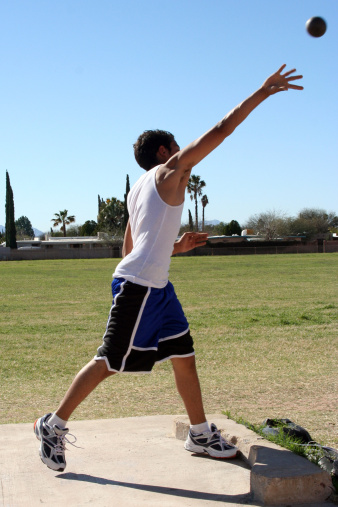 Male individual throwing a shot put in the track field events.
