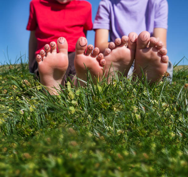 primer plano de dos pies de personas y sus dedos de los pies acostados en la hierba - barefoot behavior toned image close up fotografías e imágenes de stock