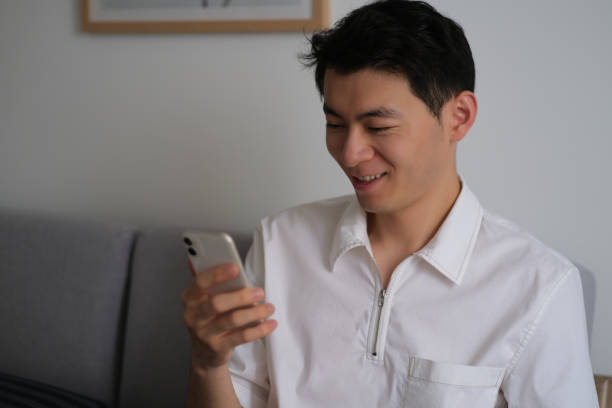 istock Asian young man looking at smartphone with smiling at home 1404470515