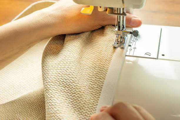 istock Female hands stitching white fabric on modern sewing machine. Close up view of sewing process. 1404471152