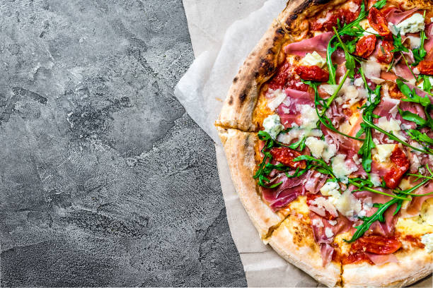 Pizza with a jamon and rucola on a gray concrete background