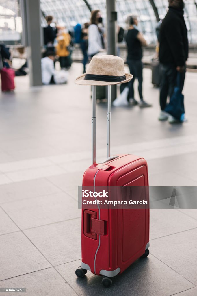 Travel and tourism concept Red suitcase with a woman hat at the train station Suitcase Stock Photo
