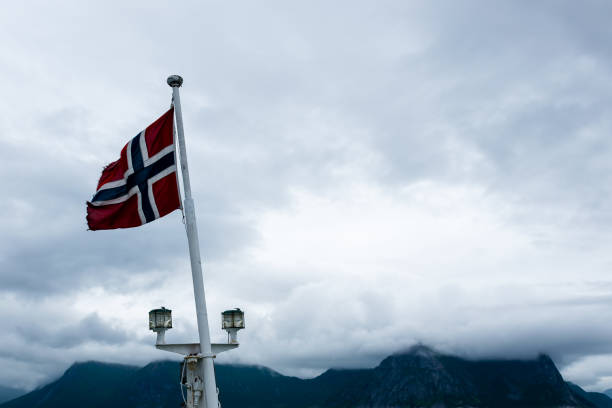 istock Norwegian flag waving on board a ship with cloud covered mountains in the background 1404473372