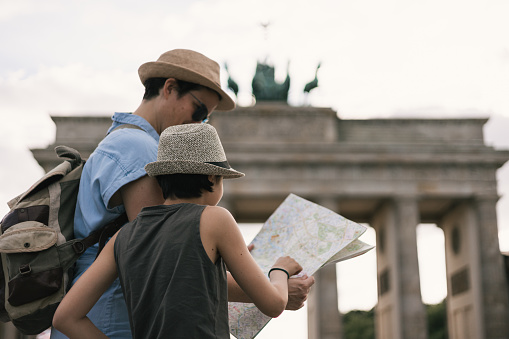 Mother and daughter tourists looking at a map at the Brandenburg gate in Berlin