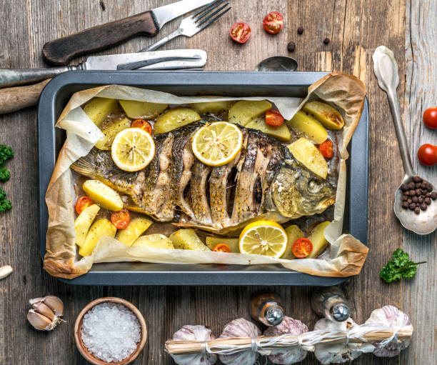 Appetizing baked fish with lemons, topview