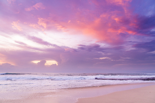 Ocean waves and sandy beach in Purple pink Sunset
