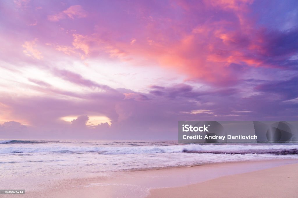 Dramatic sunset on the beach. Ocean waves and sandy beach in Purple pink Sunset Sunset Stock Photo