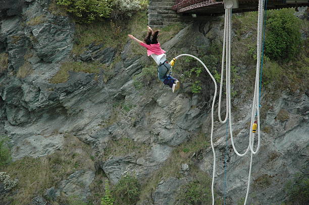 A woman bungee jumping off of a bridge This girl screams at the top of her lungs while jumping into the canyon in New Zealand (home of the bungees) bungee jumping stock pictures, royalty-free photos & images