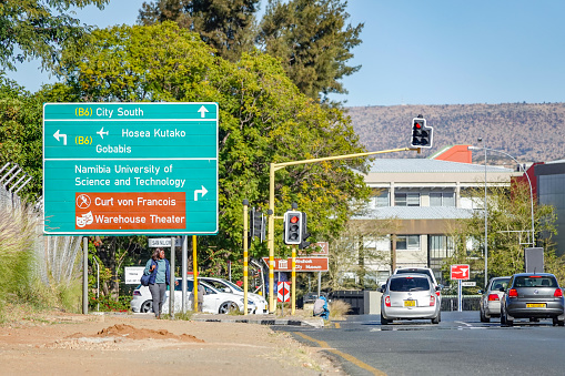 A woman walks Road Sign to Curt von Francois Statue in Windhoek at Khomas Region, Namibia, and traffic