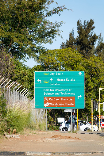 A woman walks past a Road Sign to Warehouse Theater in Windhoek at Khomas Region, Namibia