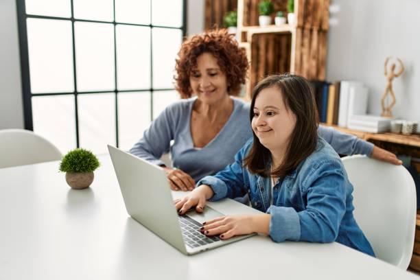 istock Mature mother and down syndrome daughter using computer laptop at home 1404479253