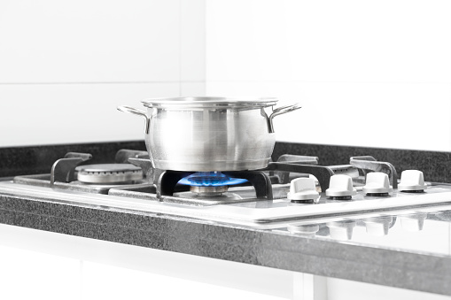 Cooking pot on the stove with a blue natural gas flame
