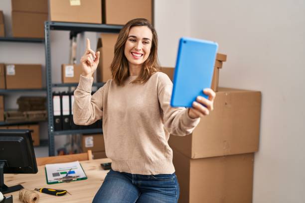 istock Young woman working ecommerce doing video with tablet smiling with an idea or question pointing finger with happy face, number one 1404480833