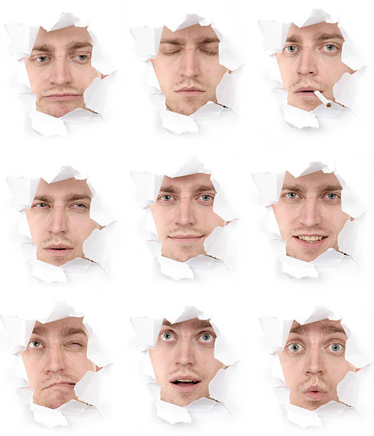 expressive faces of the emotional person in a paper hole stock photo