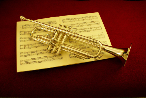 trumpet resting on sheet music and red background