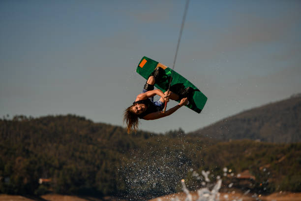 istock Active guy wakeboarder flips on wakeboard over splashing wave against sky and hills 1404481873
