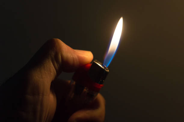 istock Hand holding burning gas lighter on dark background, bright flame close up 1404482490