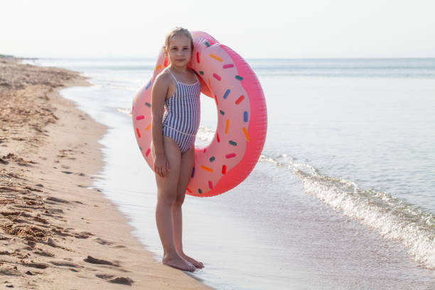 istock Relaxing kid girl with inflatable ring on the beach 1404482885