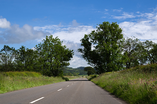 Driver view of an empty narrow country road in a Scottish location on a bright summer morning