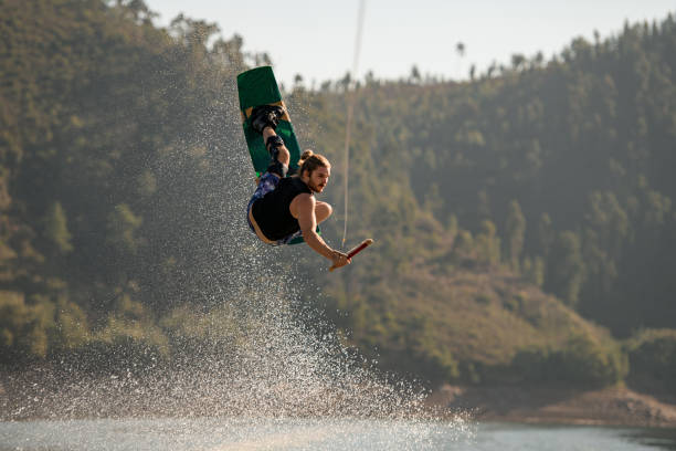 istock active male rider holds rope and making extreme jump on wakeboard. 1404483883