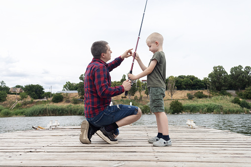 Photo of a two little boys and their parents spending quality time together while fishing on the riverbank