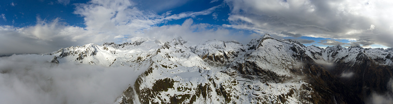 Aerial panorama landscape with clouds between snow-capped mountains