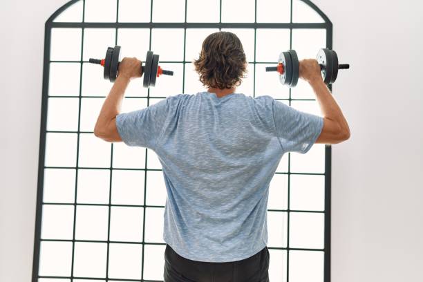 istock Middle age caucasian man on back view training using dumbbells at sport center 1404485155