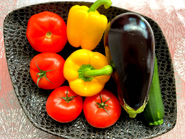 Tomatoes, peppers and eggplant on a beautiful bowl.