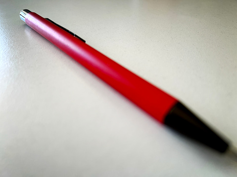 A red ballpoint pen on a white table.