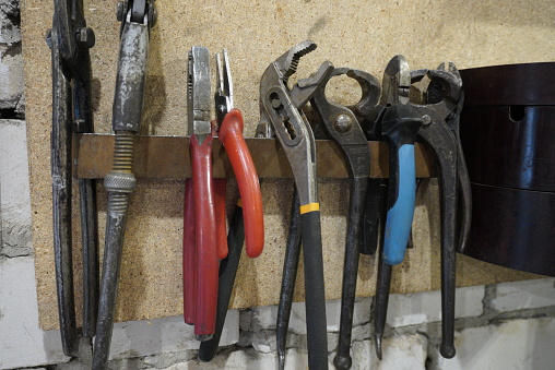 Old tools hanging on wall in workshop , Tool shelf against a wall.