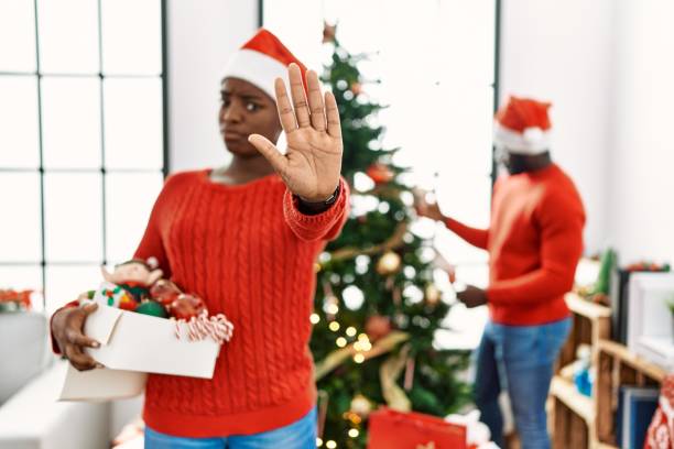 istock Young african american couple standing by christmas tree doing stop gesture with hands palms, angry and frustration expression 1404487359