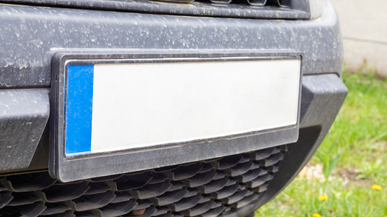 Car number without letters and numbers on the car bumper. Blank white license plate in front of the car, all logos removed, close up. The front rectangular license plate of a vehicle on the street