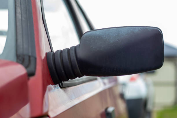 istock Side left black plastic rearview mirror on a red car. Exterior side view mirror on the driver's side on an old car. 1404490523