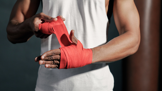 A close-up view of an African male instructor wrapping his hand before going to a fitness session.