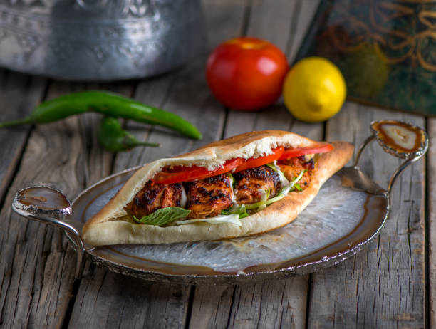 sheesh taouk sandwich served in a dish side view on wooden table background