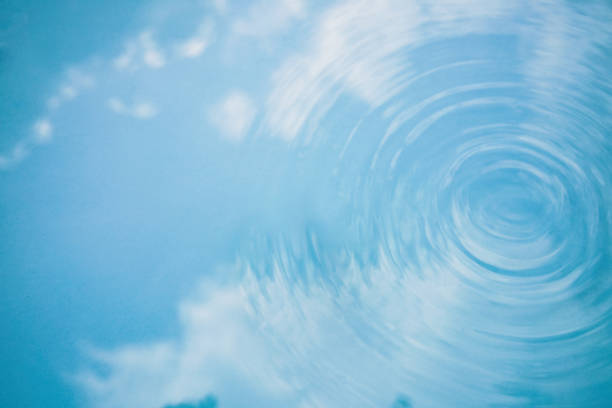 Water texture, blue sky with clouds in water with drops, ripples on surface Cosmetics and spa concept
