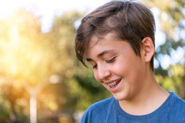 istock Smiling teenage boy wearing braces looking down 1404498154