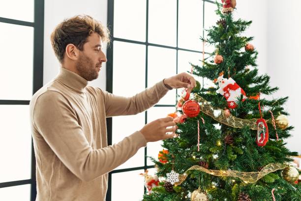 istock Young hispanic man smiling confident decorating christmas tree at home 1404498975