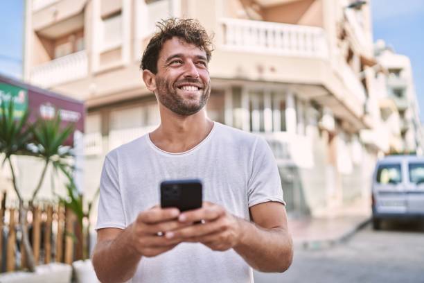 istock Young hispanic man smiling confident using smartphone at street 1404499055