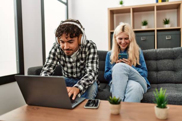 istock Young couple smling happy using laptop and smartphone at home. 1404499772