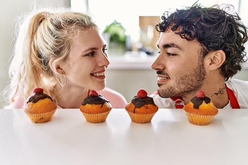 Young couple smiling happy cooking pumpkins at kitchen.